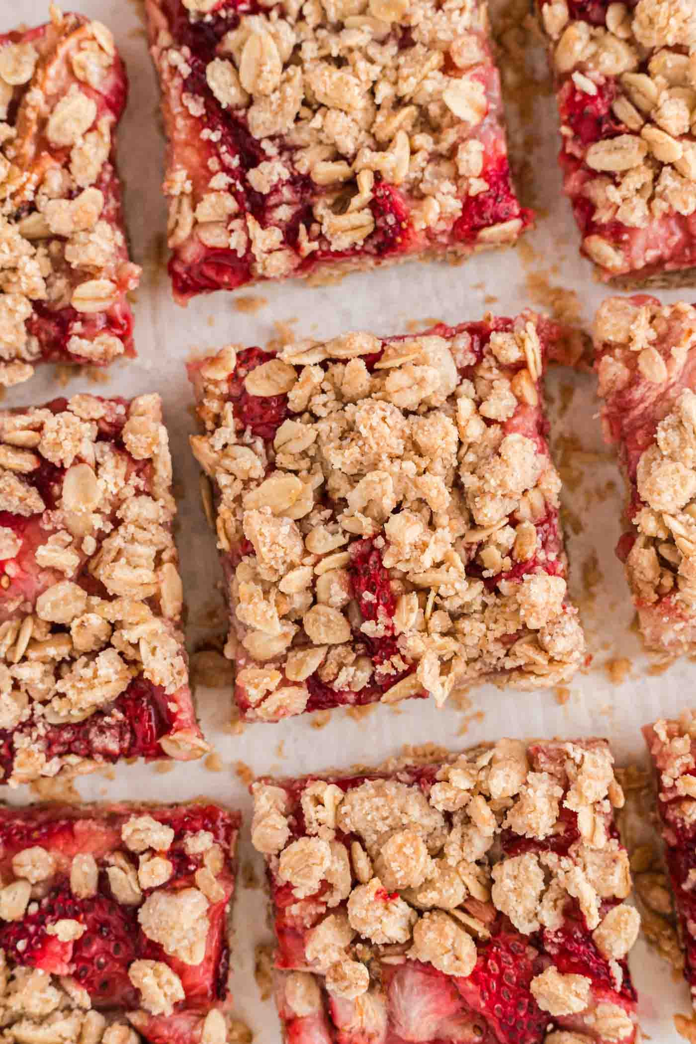 An overhead close up of a number of strawberry oat bars with an oatmeal crumble topping.