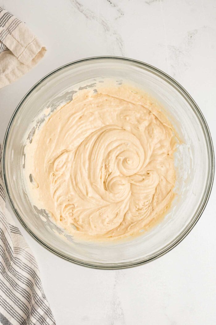 Creamy cake batter beaten together in a glass mixing bowl.