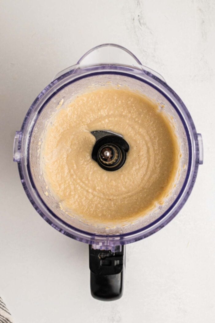 Cashews blended into a creamy but slightly grainy mixture in a food processor.