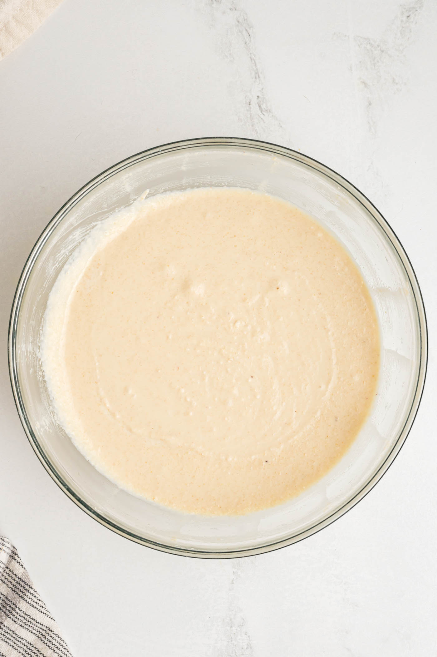 A cream cheese-like beige cream in a glass mixing bowl.