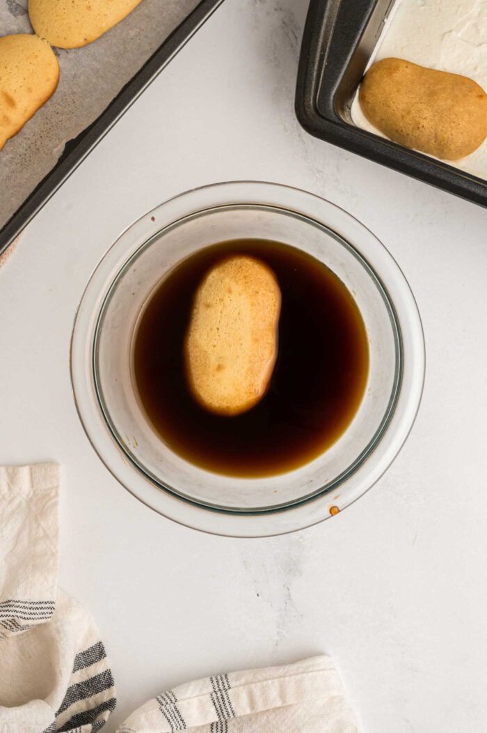 A ladyfinger cooking floating in coffee in a small bowl.