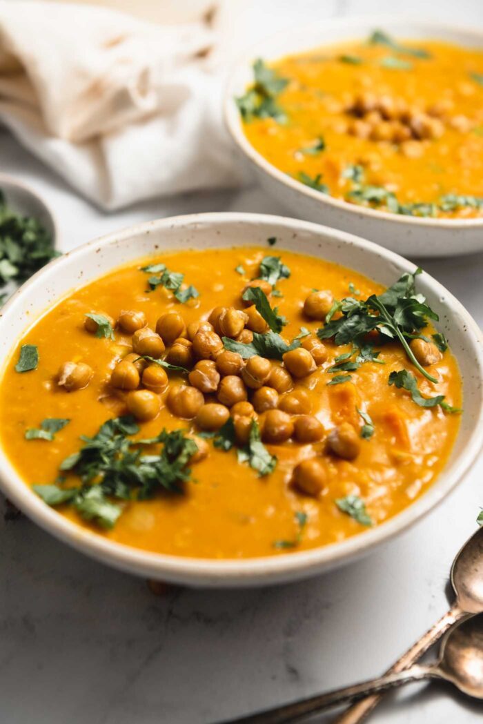 A bowl of creamy sweet potato lentil soup topped with crispy chickpeas and chopped cilantro.