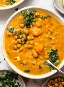 Overhead view of a creamy sweet potato carrot lentil soup topped with crispy chickpeas and a sprinkle of chopped cilantro.