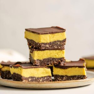 A stack of no-bake vegan Nanaimo Bars on a small plate.