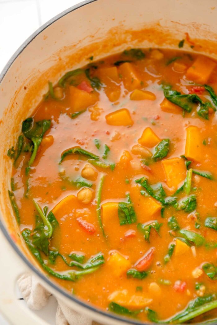 A creamy butternut squash, chickpea and spinach curry cooking in a Dutch oven.