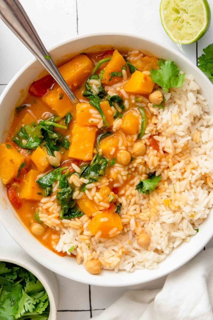 Overhead view into a bowl of creamy butternut squash curry with chickpeas and spinach served with rice.