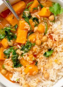 Overhead view into a bowl of creamy butternut squash curry with chickpeas and spinach served with rice.
