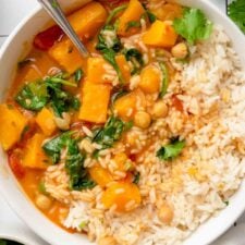 Overhead view into a bowl of creamy butternut squash curry with chickpeas and spinach served with rice.