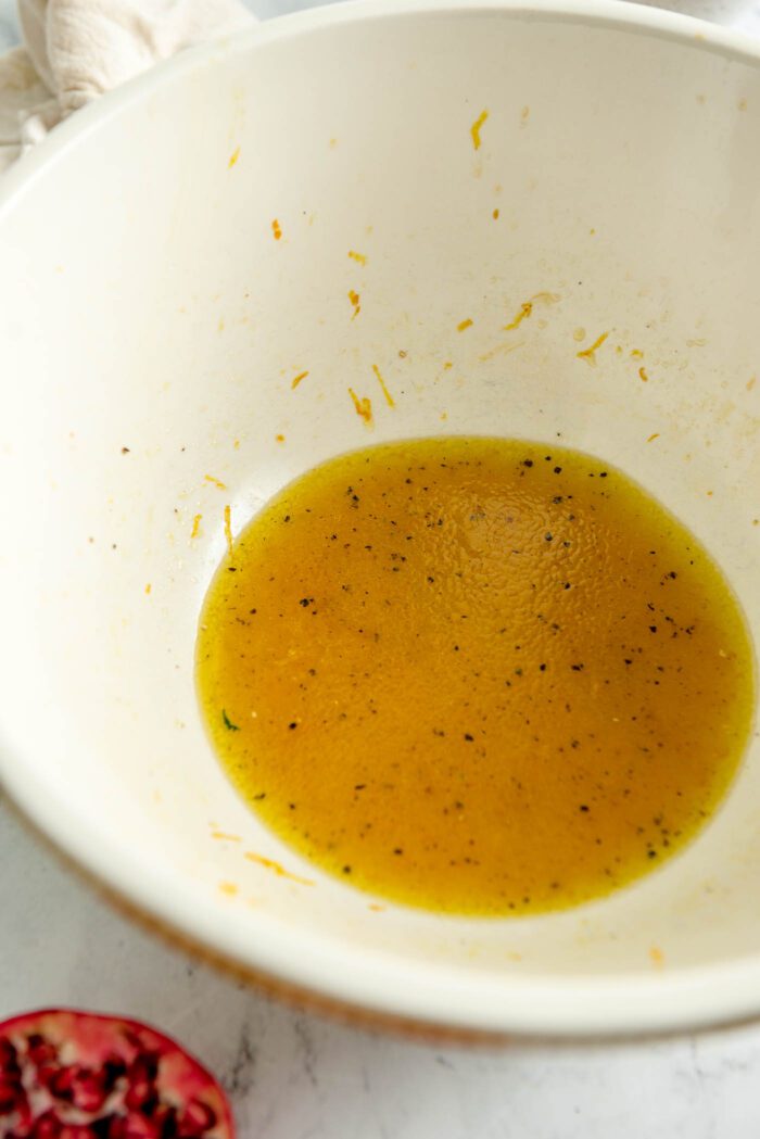 An orange vinaigrette mixed up in a large bowl.