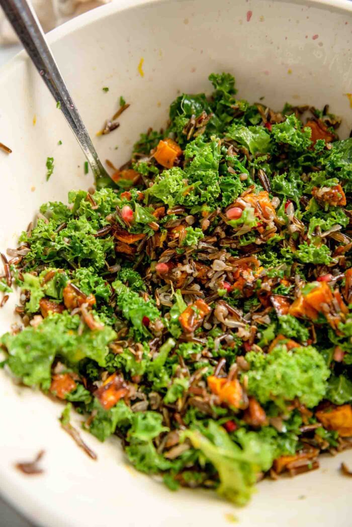 A wild rice, kale and squash salad mixed in a large mixing bowl.