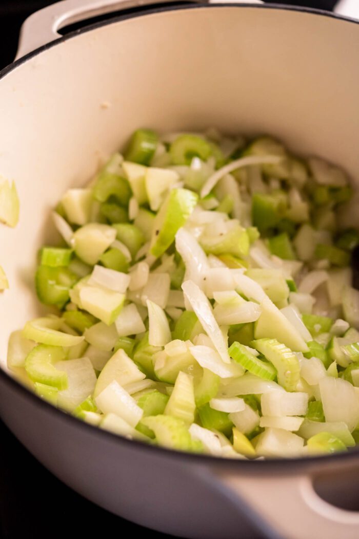Chopped celery, onion, apple and garlic cooking in a large pot.