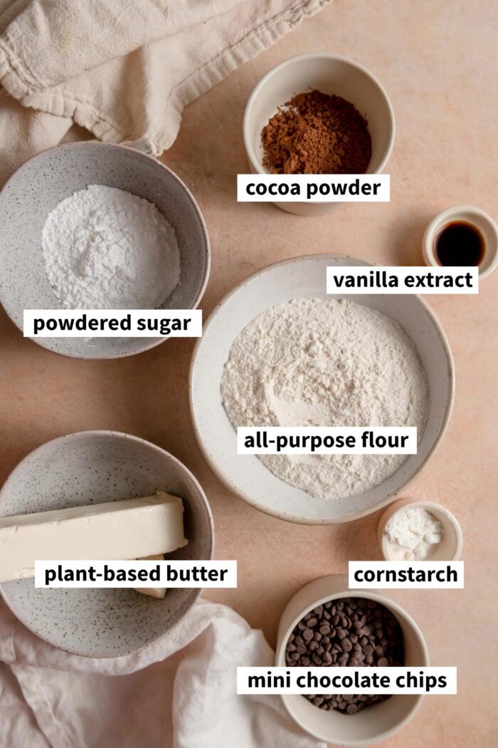 The ingredients needed for making a chocolate snowball cookie recipe. Each ingredient is labelled with text overlay.