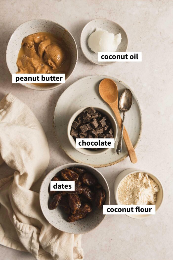 The ingredients needed for making vegan no-bake peanut butter bars, each in a bowl and labelled with text overlay.