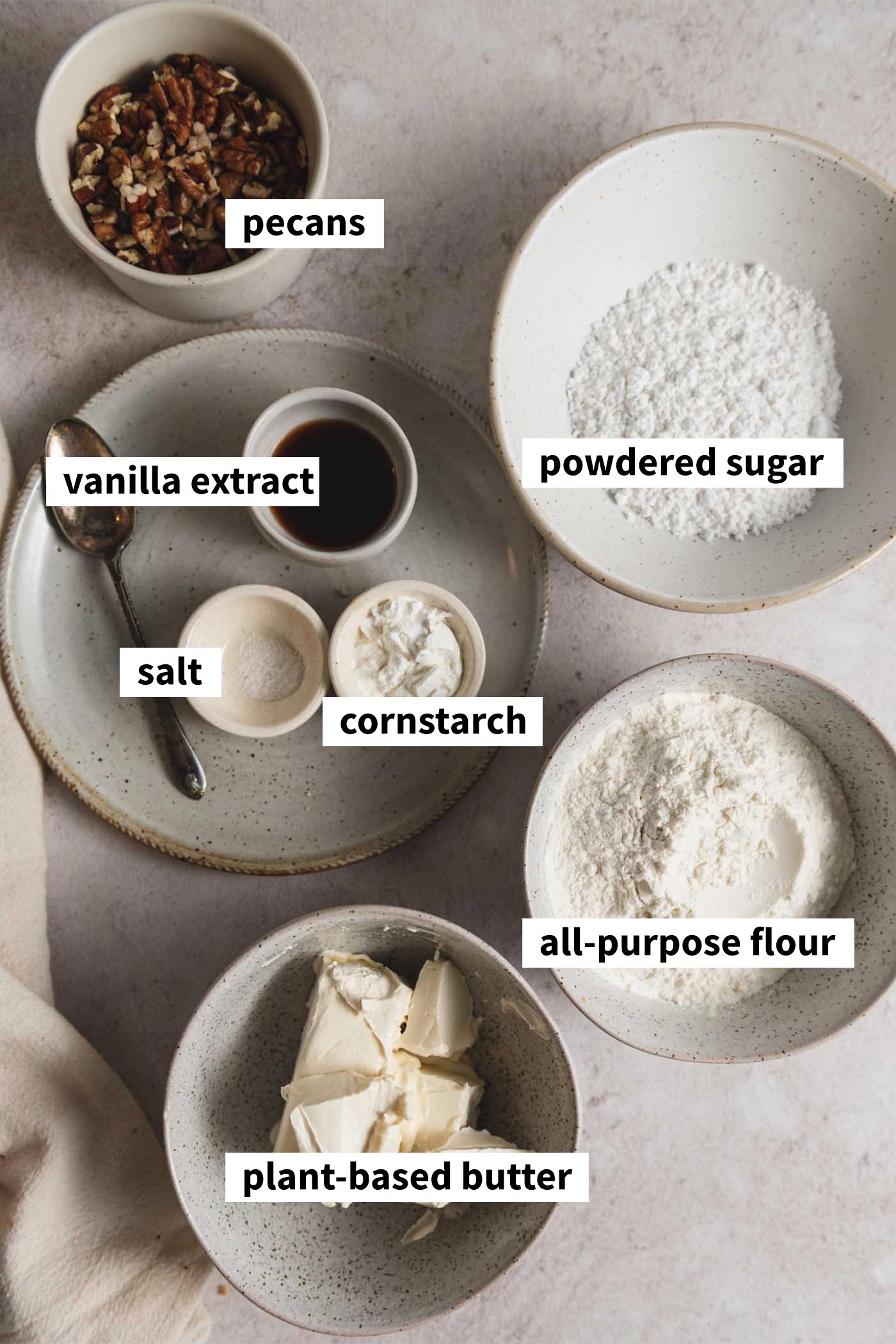 All the ingredients needed for making a pecan snowball cookie recipe. Each ingredient is labelled with text overlay.