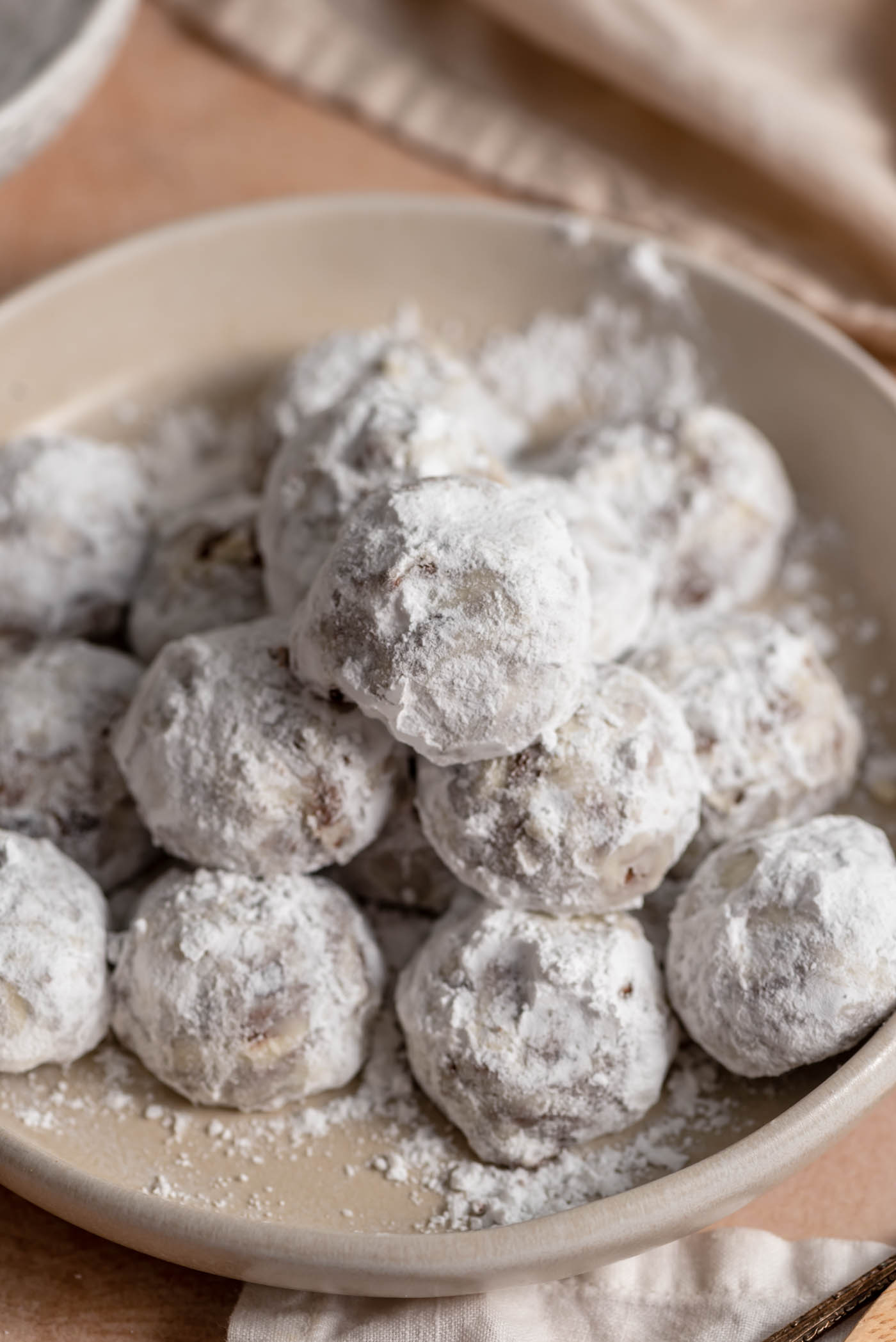 A bowl of chocolate snowball cookies that are coated in confectioners sugar.