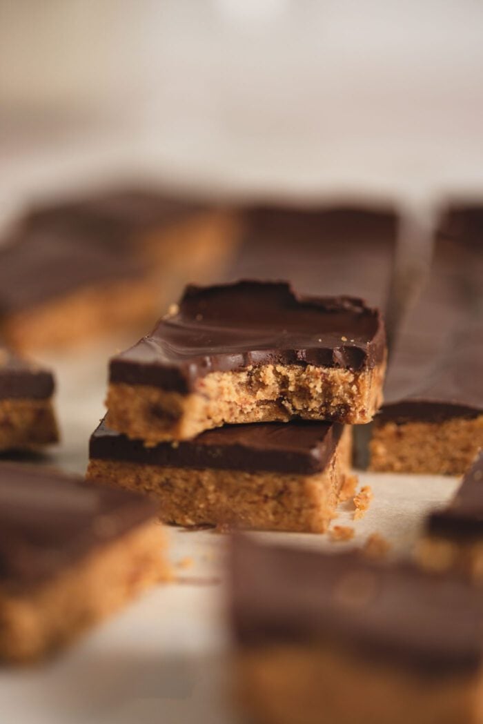 Close up of a chocolate peanut butter bar with a bite out of it sitting on top of another peanut butter bar.