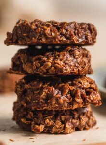 A stack of 4 vegan classic no-bake chocolate cookies sitting on a piece of parchment paper.