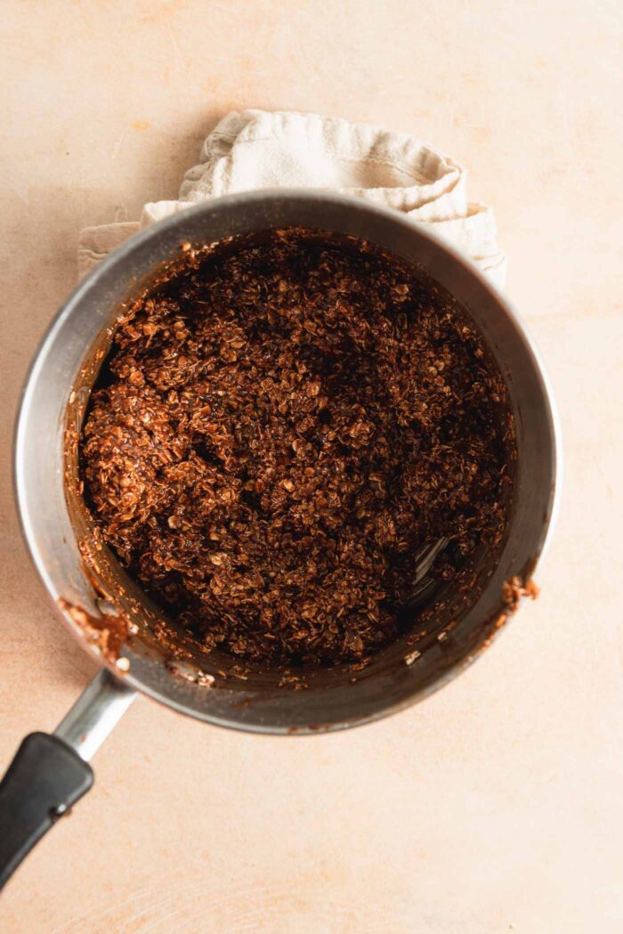 Thick chocolate oatmeal cookie dough for making classic no-bake cookies in a small saucepan.