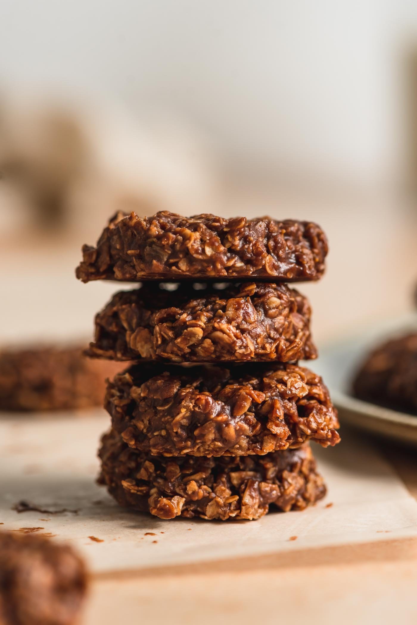 A stack of 4 vegan classic no-bake chocolate cookies sitting on a piece of parchment paper.