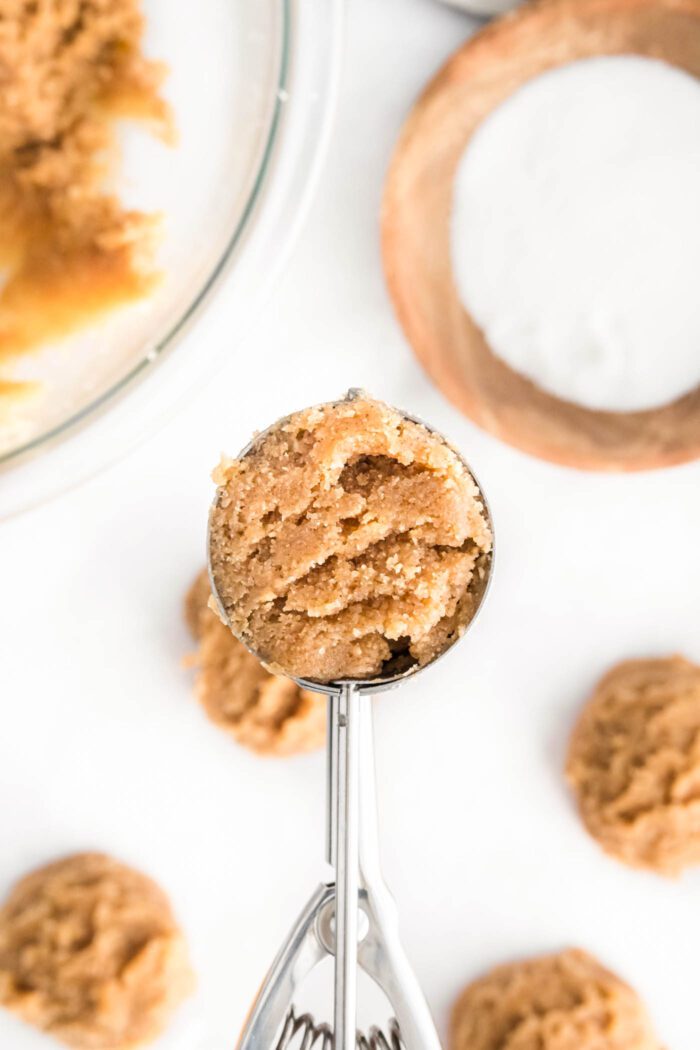 Peanut butter cookie dough in a small metal cookie scoop.
