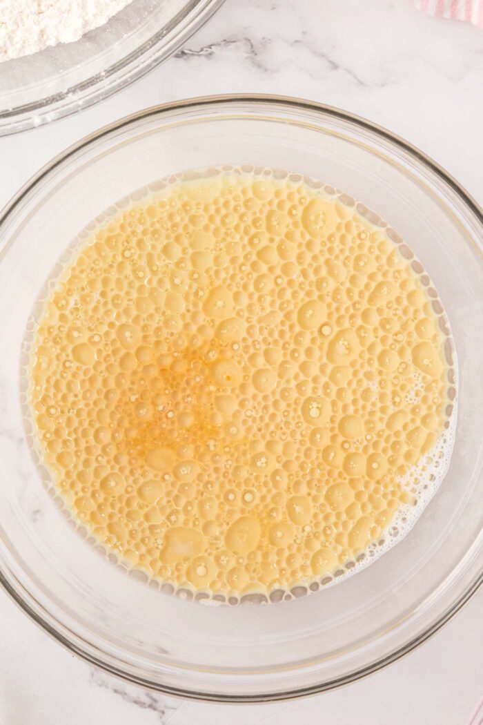 A bubbly liquid mixture in a glass mixing bowl.