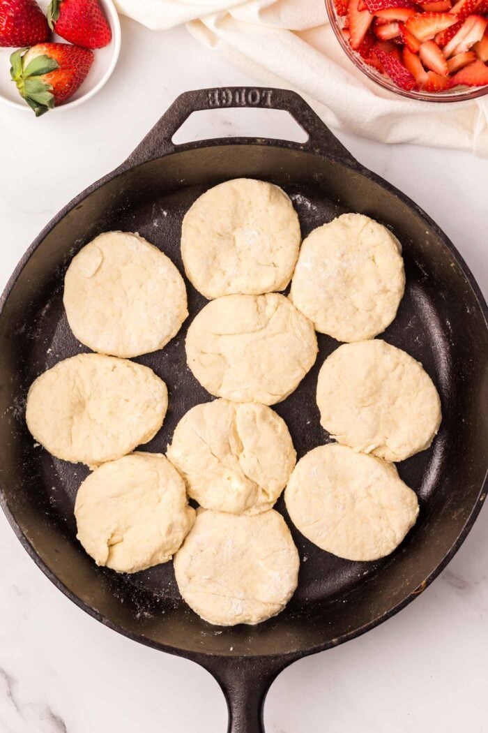 Raw biscuits in a cast iron skillet.