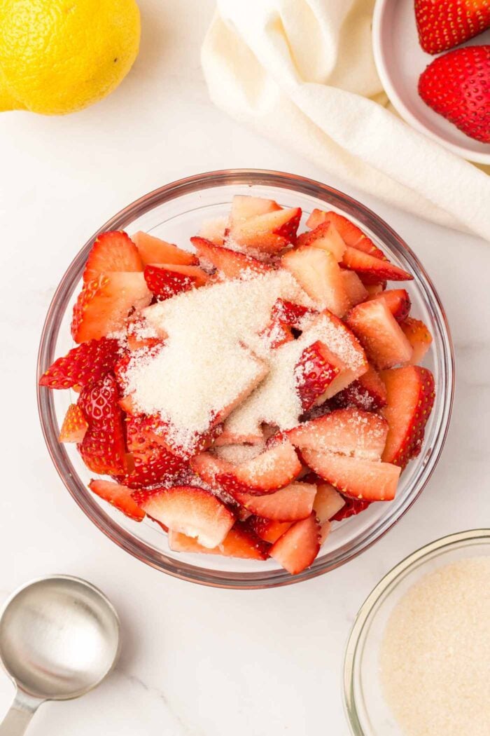 Sliced strawberries topped with sugar in a bowl.