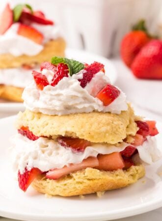 A pretty strawberry shortcake with a homemade biscuit filling and topped with whipped cream and sliced strawberries.