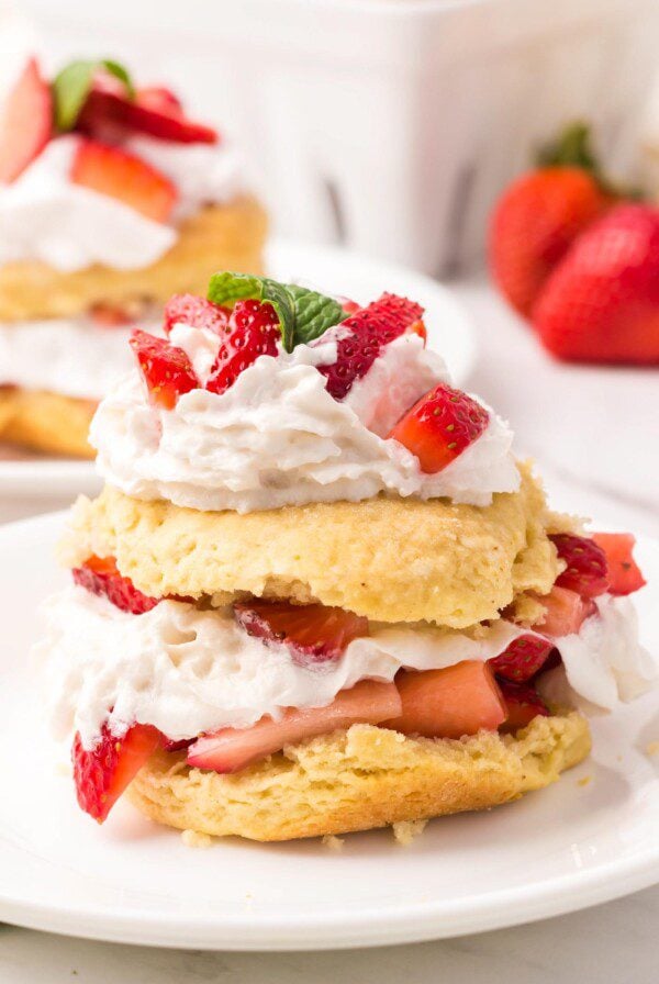 A pretty strawberry shortcake with a homemade biscuit filling and topped with whipped cream and sliced strawberries.