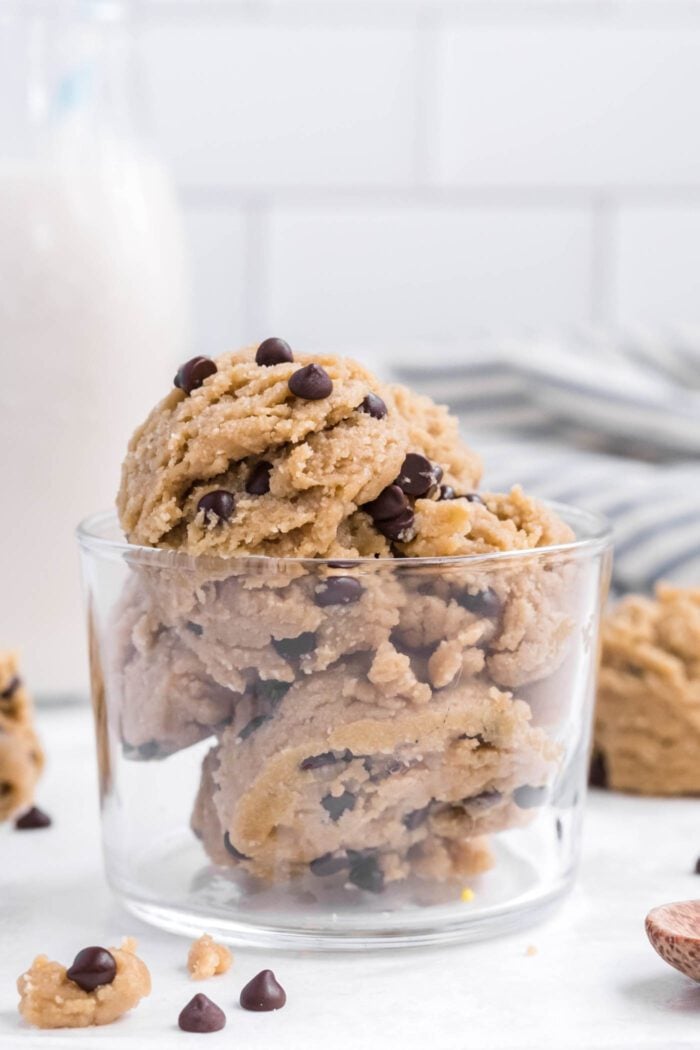 A small glass bowl with a few scoops of edible chocolate chip cookie dough in it.