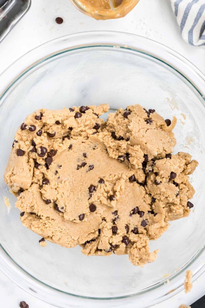 Edible chocolate chip cookie dough in a glass mixing bowl.