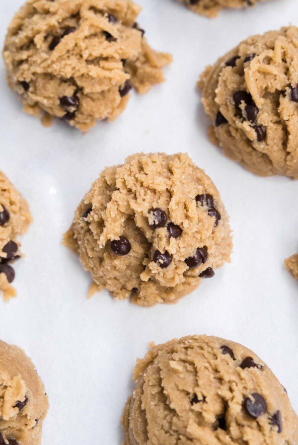 Overhead close up of scoops of chocolate chip cookie on a baking sheet.