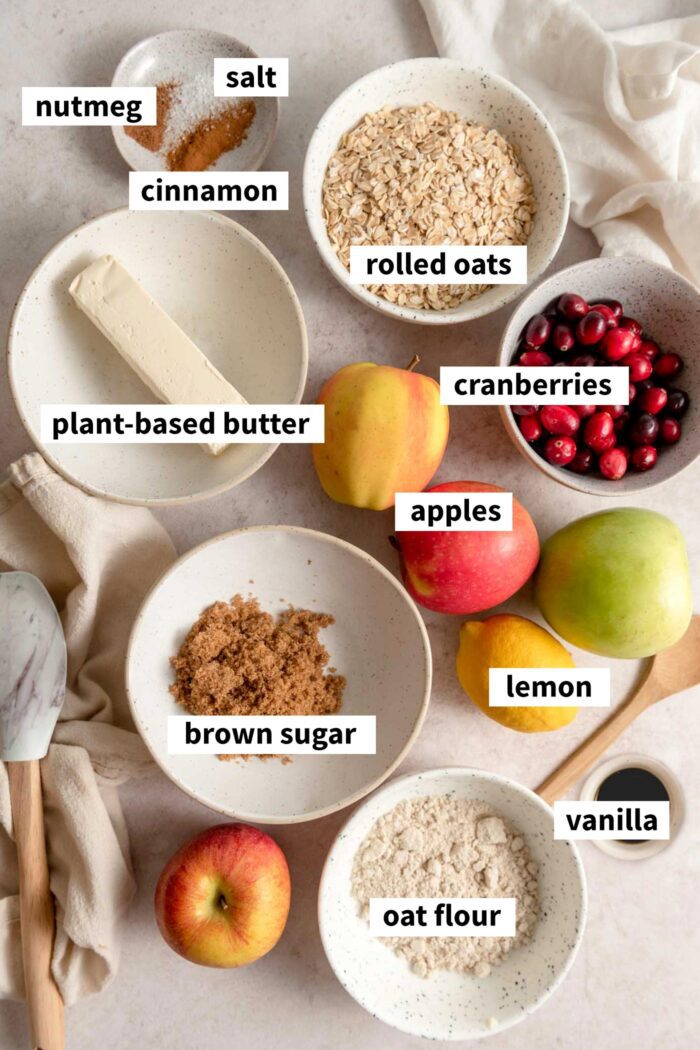 All the ingredients for apple cranberry crisp recipe. Each ingredient is labelled with text.