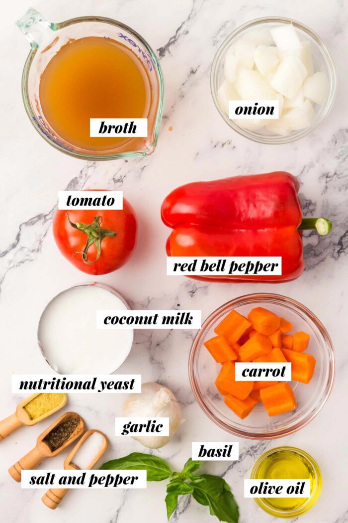 All of the ingredients needed for making a creamy vegan tomato basil soup recipe. Each ingredient is labelled with text.