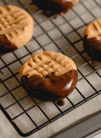 A peanut butter cookie that's dipped in chocolate covering half of the cookie.