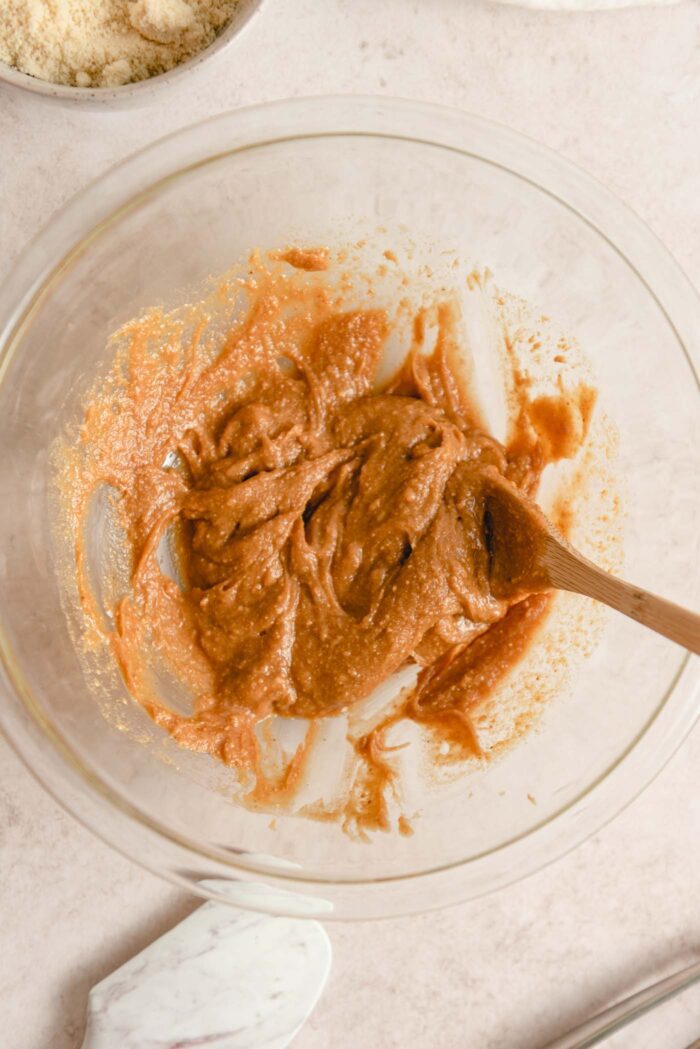 Peanut butter and maple syrup mixed together in a glass mixing bowl.