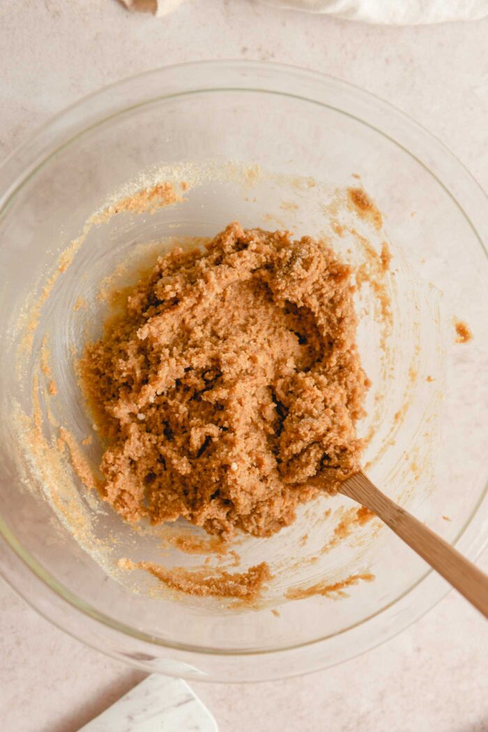 Almond flour peanut butter cookie dough in a glass mixing bowl with a wooden spoon.