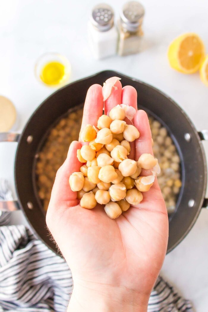 A hand holding a handful of chickpeas.