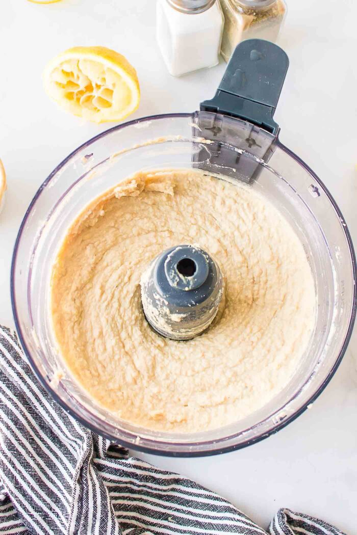 Smooth and creamy hummus in a food processor container.