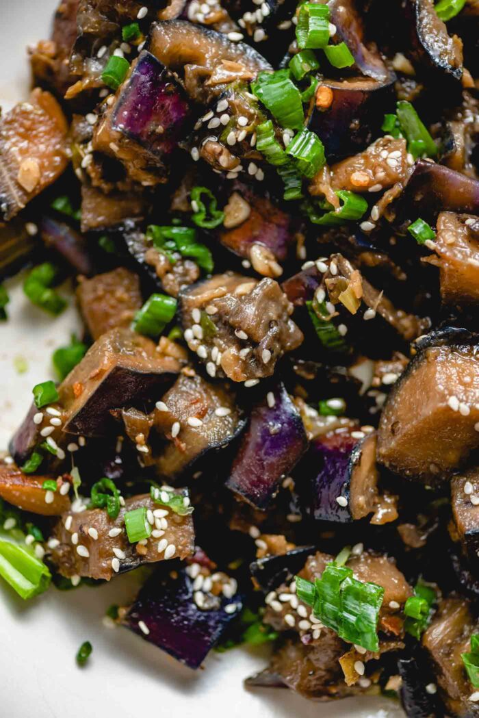 Close up of stir fried eggplant with green onion and sesame seeds in a bowl.