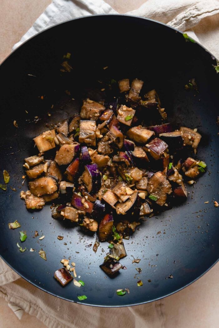 Eggplant stir fry with green onion, garlic and ginger in a wok.