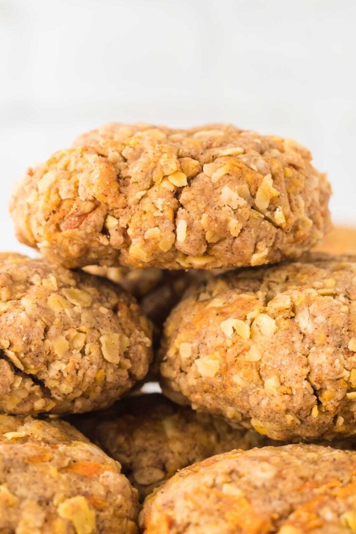 A close up of a few carrot cake oatmeal cookies stacked on top of each other.