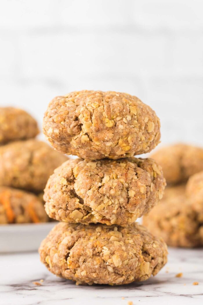 A stack of 3 vegan oatmeal carrot cookies on a marble surface.