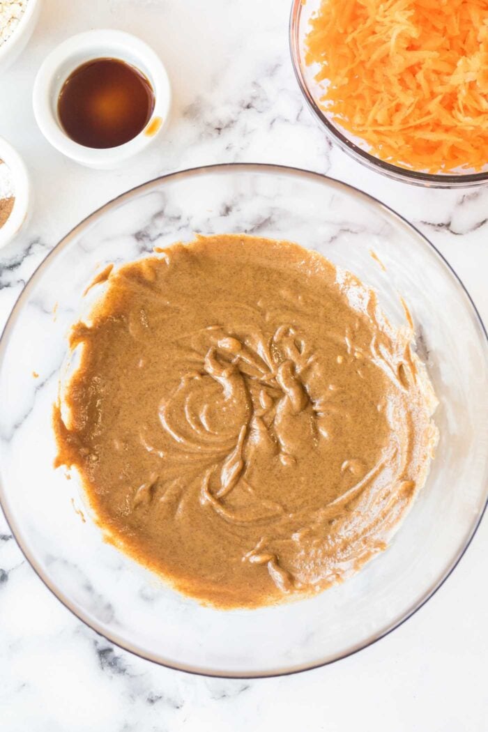 Almond butter and sugar mixed together in a glass mixing bowl.