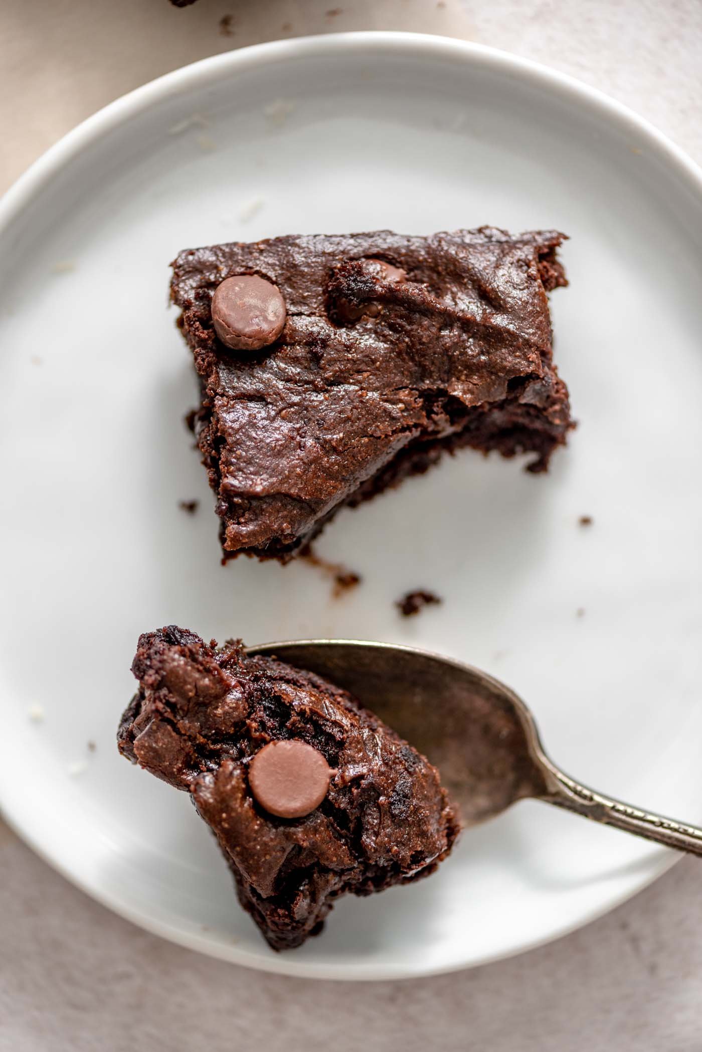 A brownie split in two by a spoon on a small plate.