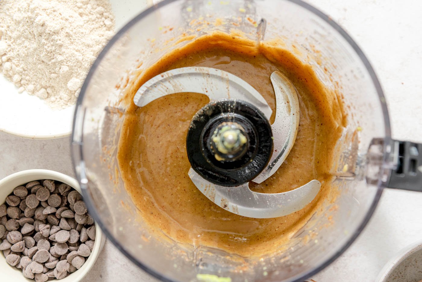 A creamy caramel-like mixture in the bowl of a food processor.