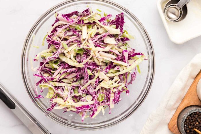 Creamy red and green cabbage slaw in a glass mixing bowl.