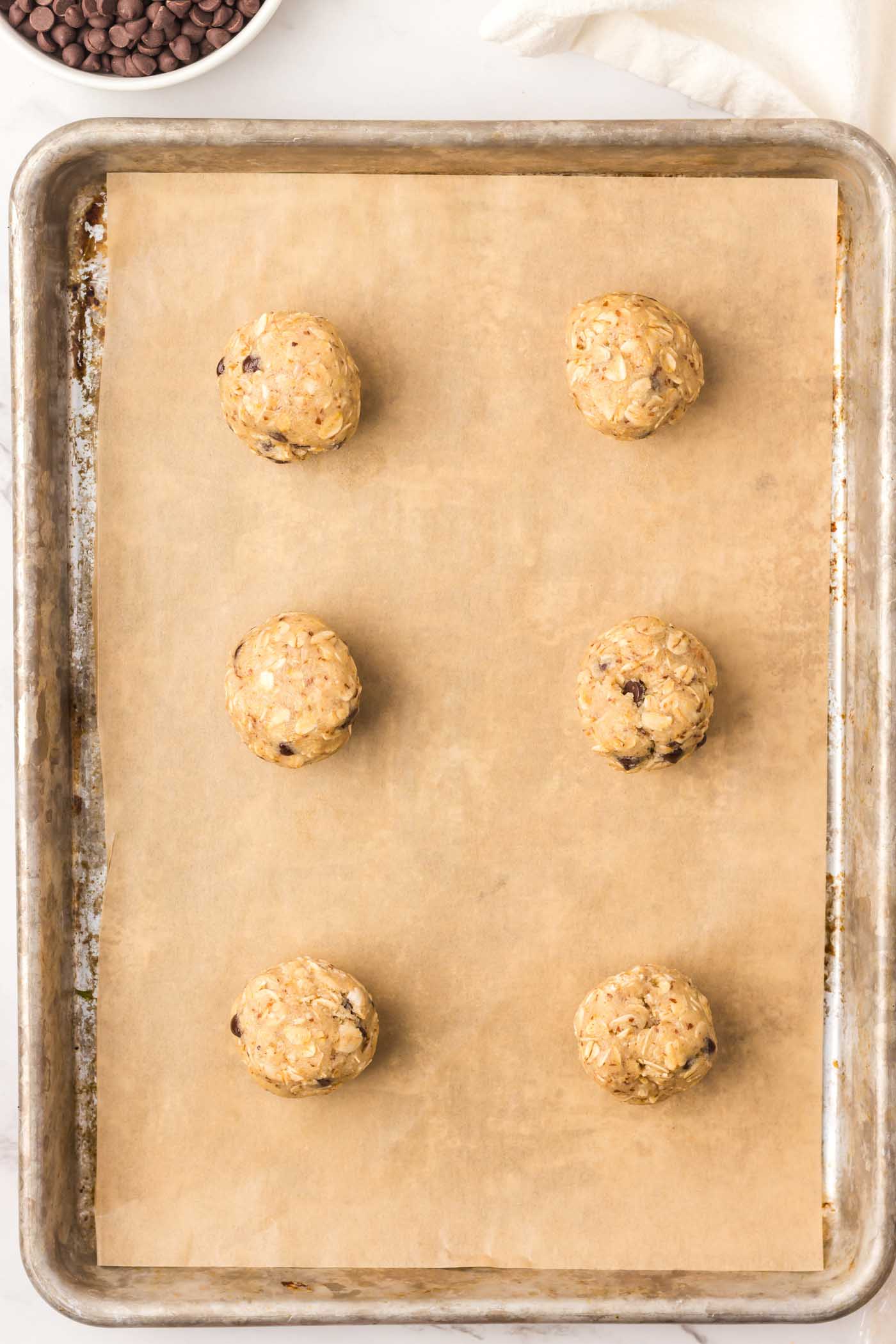 6 balls of almond flour oatmeal cookies on a baking sheet before baking.