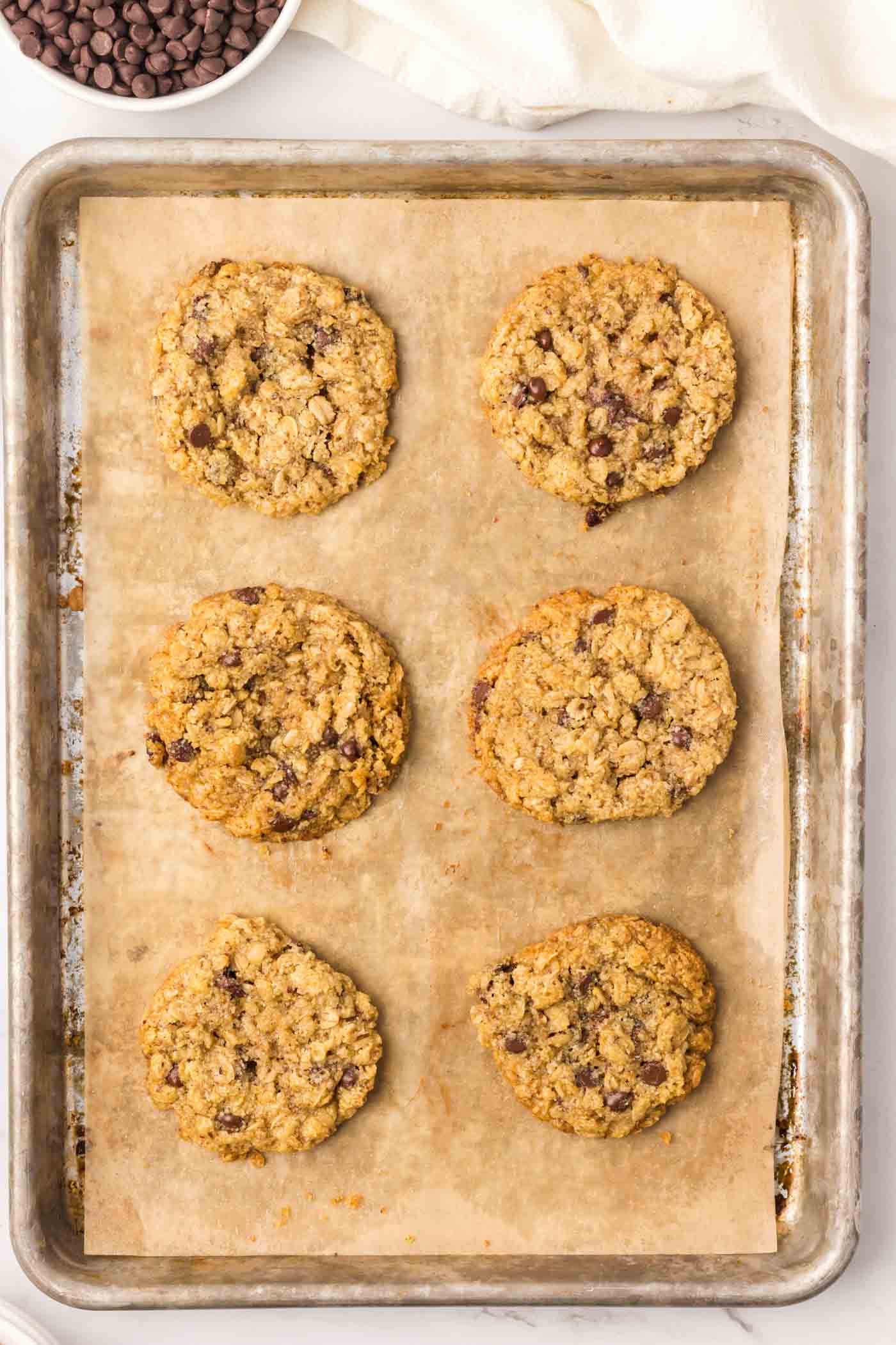 6 almond almond oatmeal chocolate chip cookies on a baking sheet.