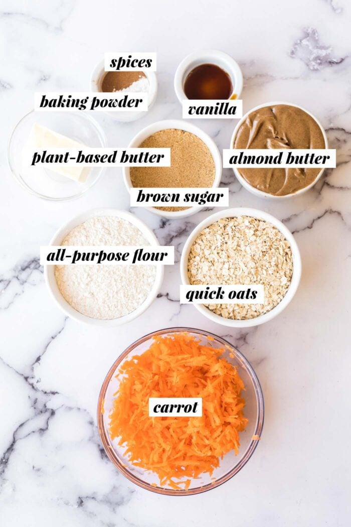 All the ingredients needed for making a vegan carrot cake cookie recipe with oats, brown sugar, almond butter and all-purpose flour.